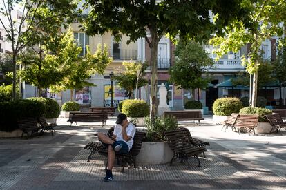 Un joven consulta su teléfono móvil en una plaza vacía en Chamberí.