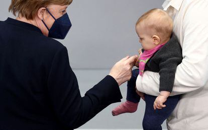 Former Chancellor Angela Merkel greets a baby during the federal assembly to re-elect Frank-Walter Steinmeier as president.