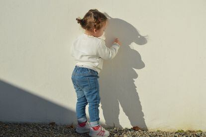 Una niña escribe con su dedo en una pared.