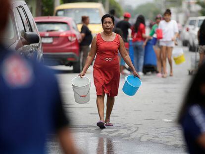 Una mujer carga cubetas a un centro público de distribución de agua en Escobedo, Nuevo León, el 21 de abril de 2022. 