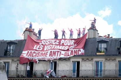 Activistas de extrema derecha deslizan una pancarta que pide justicia para las víctimas del racismo anti-blanco en una azotea de París el 13 de junio de 2020.