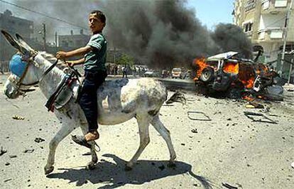 Un niño palestino pasa montado en un burro ante el coche del líder de Hamás, Abdelaziz Rantisi, tras el ataque israelí en Gaza, ayer.