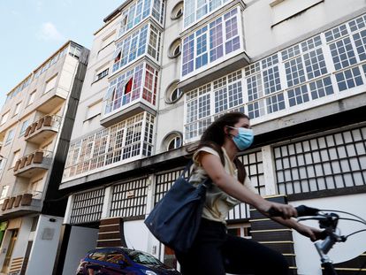 Una mujer monta en bicicleta junto al edificio 41 de la calle Duquesa de Alba, en la localidad lucense de Monforte de Lemos, que ha sido confinado por el Servizo Galego de Saúde.