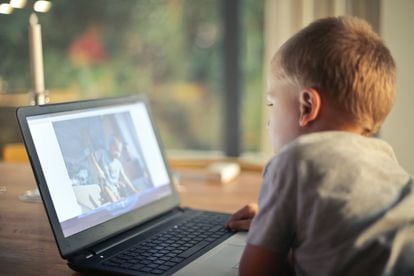 Un niño mira su ordenador en casa.