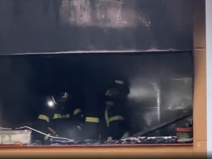 Dos bomberos, durante la extinción del fuego que ha afectado a una vivienda de la calle de Telémaco en Madrid.