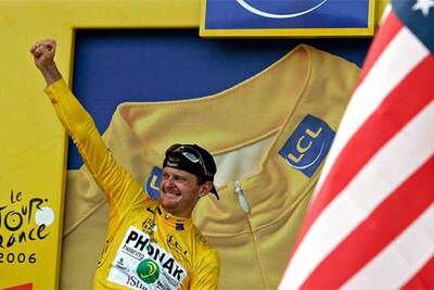 Landis, ya vestido con el jersey de líder, en el podio de fin de etapa junto a la bandera de su país.