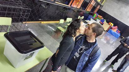 Una parella es petoneja al costat d'una de les urnes del referèndum independentista en l'institut Lanaspa de Terrassa, Vallès Occidental.
