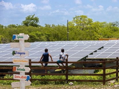 Dos niños conversan sentados en la cerca de una planta solar en el Parque Nacional del Este Cotubanamá en la Isla Saona (República Dominicana).