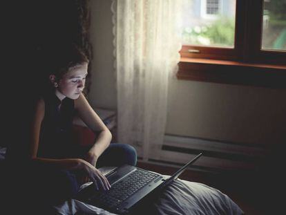 Una niña utiliza un ordenador portátil en su habitación. / GETTY IMAGES