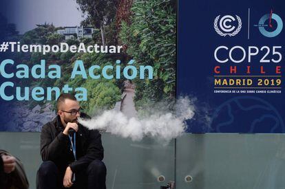Un hombre fuma un cigarrillo electrónico en la entrada de la Cumbre del Clima que se celebra en Madrid. 