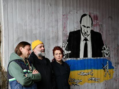 Desde la izquierda, el dramaturgo Mijaíl Durnenkov, el artista visual Pável Semchenko y su mujer, la escenógrafa Anis Kvonidova, delante de un grafiti contra Putin en Helsinki.