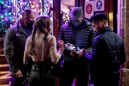 Tres personas muestran su pasaporte covid a la entrada de un local de ocio que ha entrado en vigor esta medianoche en la Comunidad Valenciana.