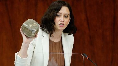 La presidenta de la Comunidad de Madrid, Isabel Díaz Ayuso, muestra un adoquín en la Asamblea de Madrid el pasado febrero.