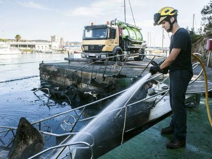 Un bombero extingue las llamas de uno de los barcos.