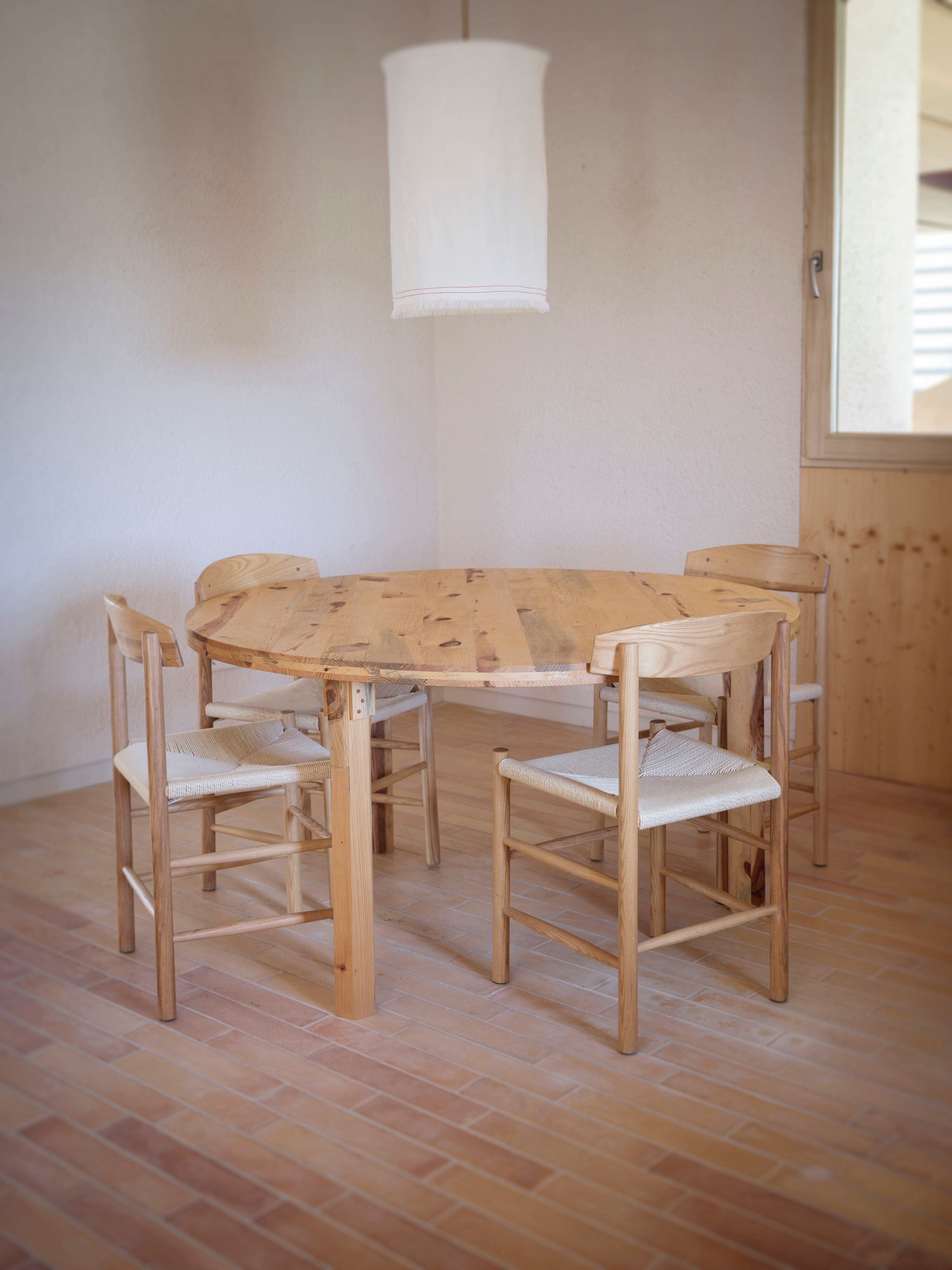 Modelo Taula Rodona de la marca, fabricada íntegramente en madera de pino local. Las sillas son también de Amarar.