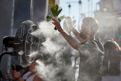 Un joven se refresca del calor con el difusor de vapor de agua de un restaurante de la calle Alcalá de Madrid, el pasado 2 de julio.