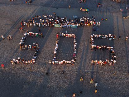 Los vecinos y veraneantes de Sagunto y Canet formaron ayer las letras SOS en la playa que limita ambos municipios.