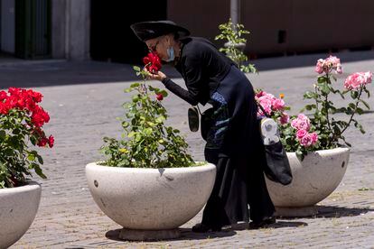 Una mujer se baja la mascarilla para oler unas rosas en Roma, el pasado mayo, en pleno confinamiento.