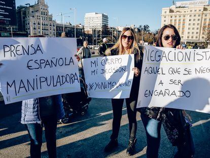 Tres mujeres sostienen diferentes pancartas durante una manifestación negacionista, el 11 de diciembre de 2021 en Madrid.