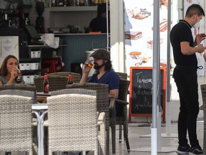 Un camarero atiende a unos clientes en la terraza de un bar. 