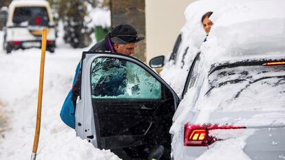 Un hombre despeja la nieve para poder acceder a su vehículo en el pueblo de Pajares (Asturias).