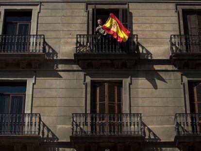 Un hombre ondea una bandera de España en un balcón durante la manifestación convocada en Barcelona el 8 de octubre.