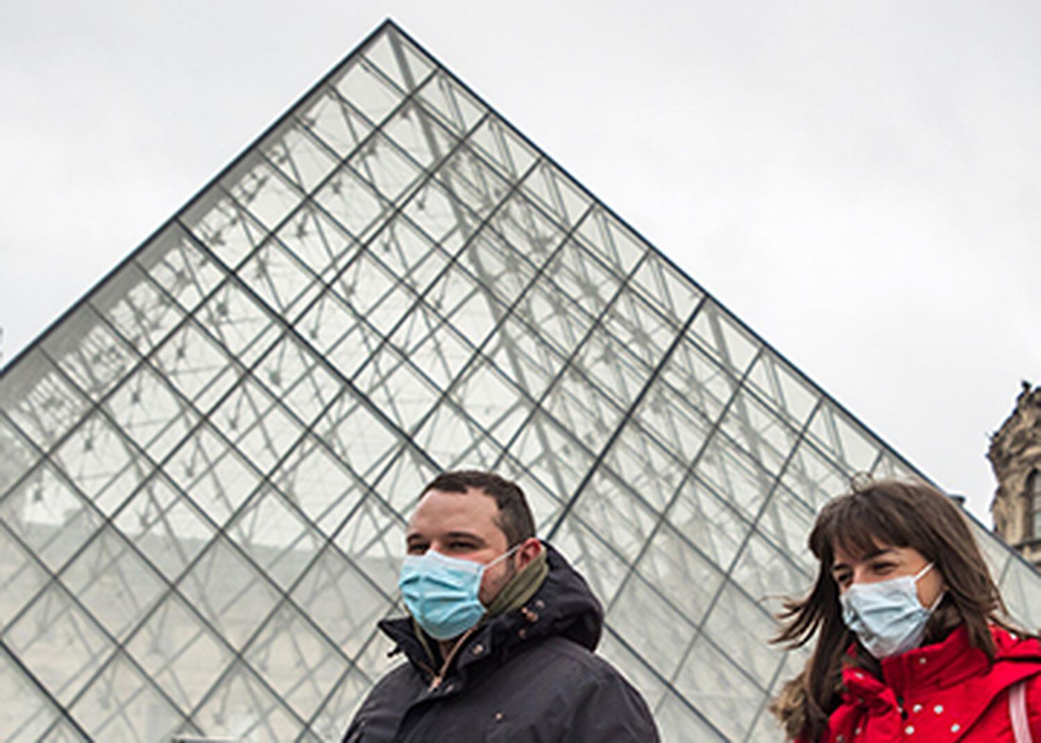 Dos personas con mascarillas pasan frente al Museo del Louvre de París.