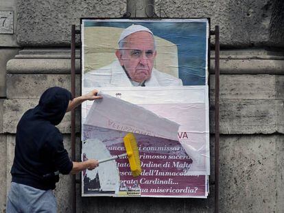 Un operario cubre un cartel contra el Papa en una calle de Roma.