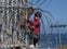 A boy is helped by a man while climbing a fence in the area at the border of Morocco and Spain, outside the Spanish enclave of Ceuta, Tuesday, May 18, 2021. Ceuta, a Spanish city of 85,000 in Northern Africa, faces a humanitarian crisis after thousands of Moroccans took advantage of relaxed border control in their country to swim or paddle in inflatable boats into European soil. By Tuesday afternoon, nearly 8,000 people had crossed the border into the city since early Monday, the Spanish government said, including some 2,000 thought to be teenagers. (AP Photo/Mosa'ab Elshamy)