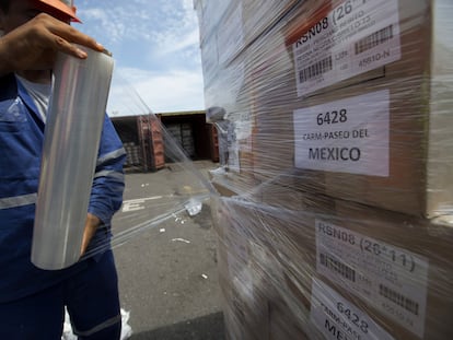 Un trabajador envuelve cajas en plástico antes de cargarla en un contenedor de envío en el Puerto de Veracruz.
