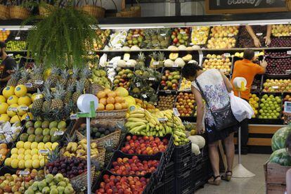 Una mujer elige fruta en un mercado. 
