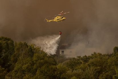 Un helicóptero realiza labores de extinción el miércoles en el incendio forestal en Verín, cerca de varias viviendas, el miércoles.