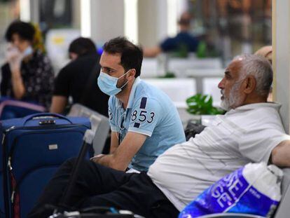 Viajeros esperan sentados con sus maletas en el Aeropuerto Internacional de Bagdad (Irak). 