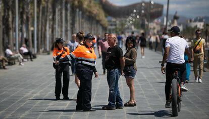 Un agent cívic assenyala el carril bici a un ciclista en el passeig Marítim de Barcelona.