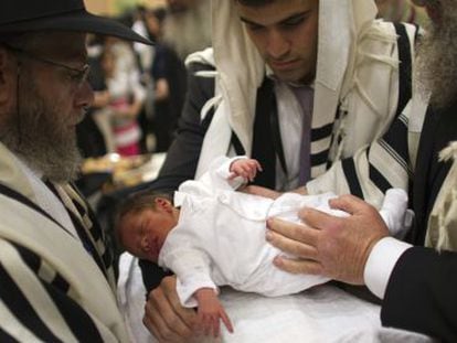 Un judío ortodoxo sostiene a su hijo durante su circuncisión en Jerusalén.