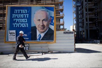 Un hombre camina frente a un cartel electoral de Netanyahu en Tel Aviv.