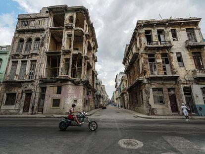 Una motocicleta pasa frente a dos edificios semidestruidos en La Habana, Cuba.