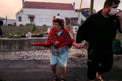 Una mujer es evacuada de su casa durante el incendio forestal en la localidad portuguesa de Cascais, este martes.
