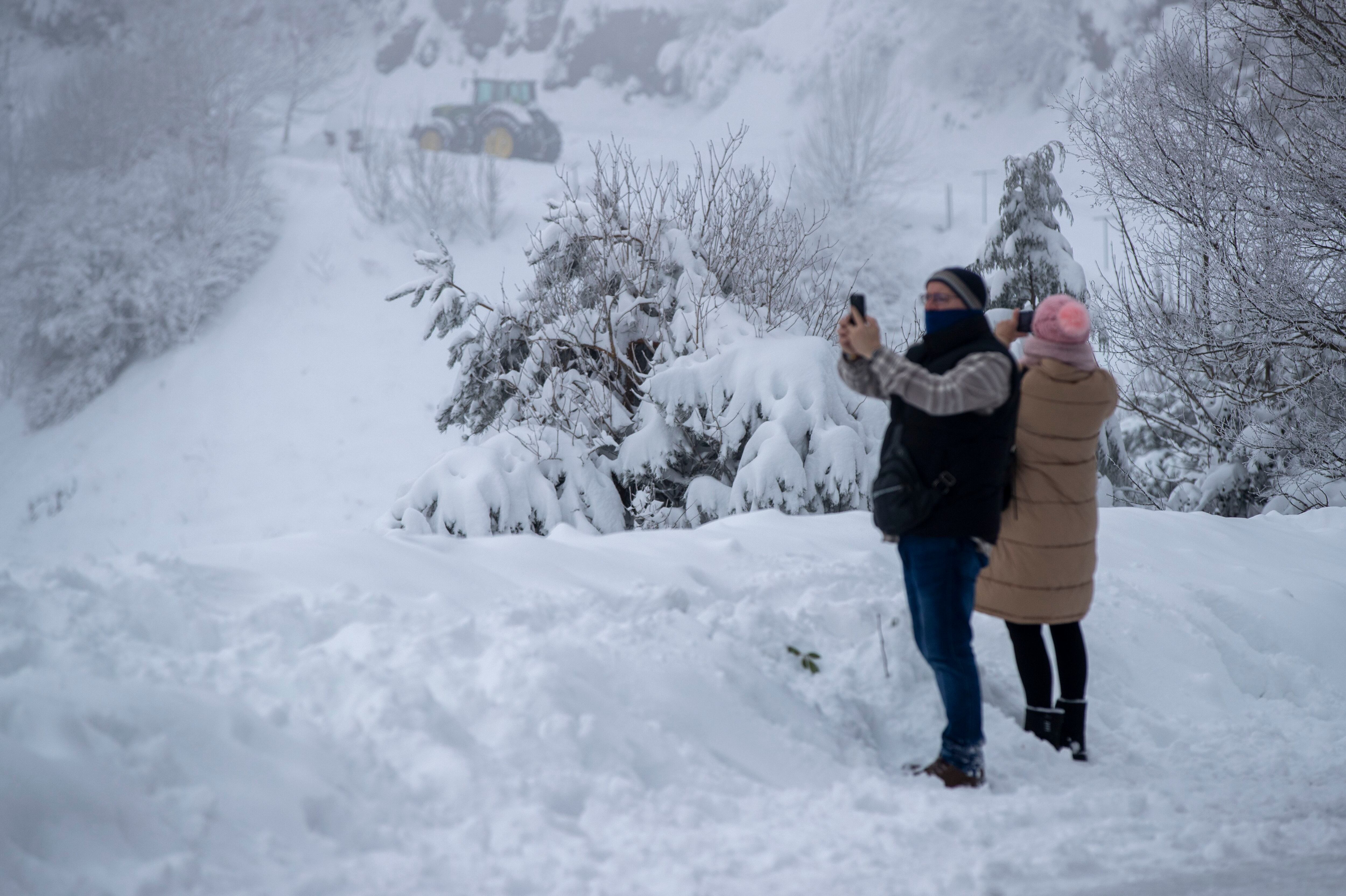Un grupo de personas se divierte fotografiando la nieve, que cubre la totalidad de la calzada, este miércoles en Pedrafita do Cebreiro.