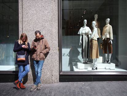 Una pareja consulta sus teléfonos móviles frente al escaparate de una tienda en el centro de Madrid.