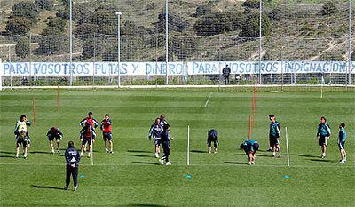 Los jugadores del Madrid se ejercitan durante el entrenamiento de ayer ante la pancarta que unas personas colgaron de la valla.