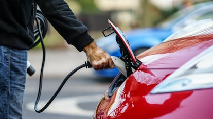 Un conductor carga su coche eléctrico en la calle.