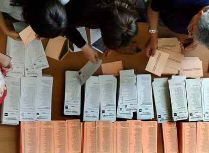 Varios electores cogen ayer papeletas en un colegio electoral.