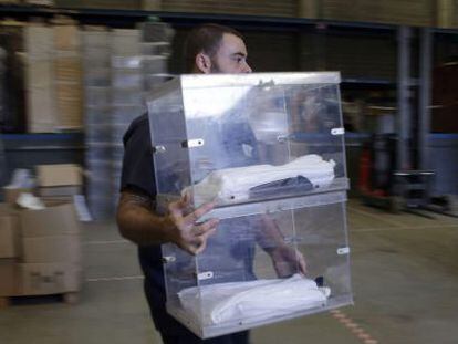 Un operario de la empresa encargada de repartir el material electoral trasnporta una urna en el almac&eacute;n municipal de Barcelona.