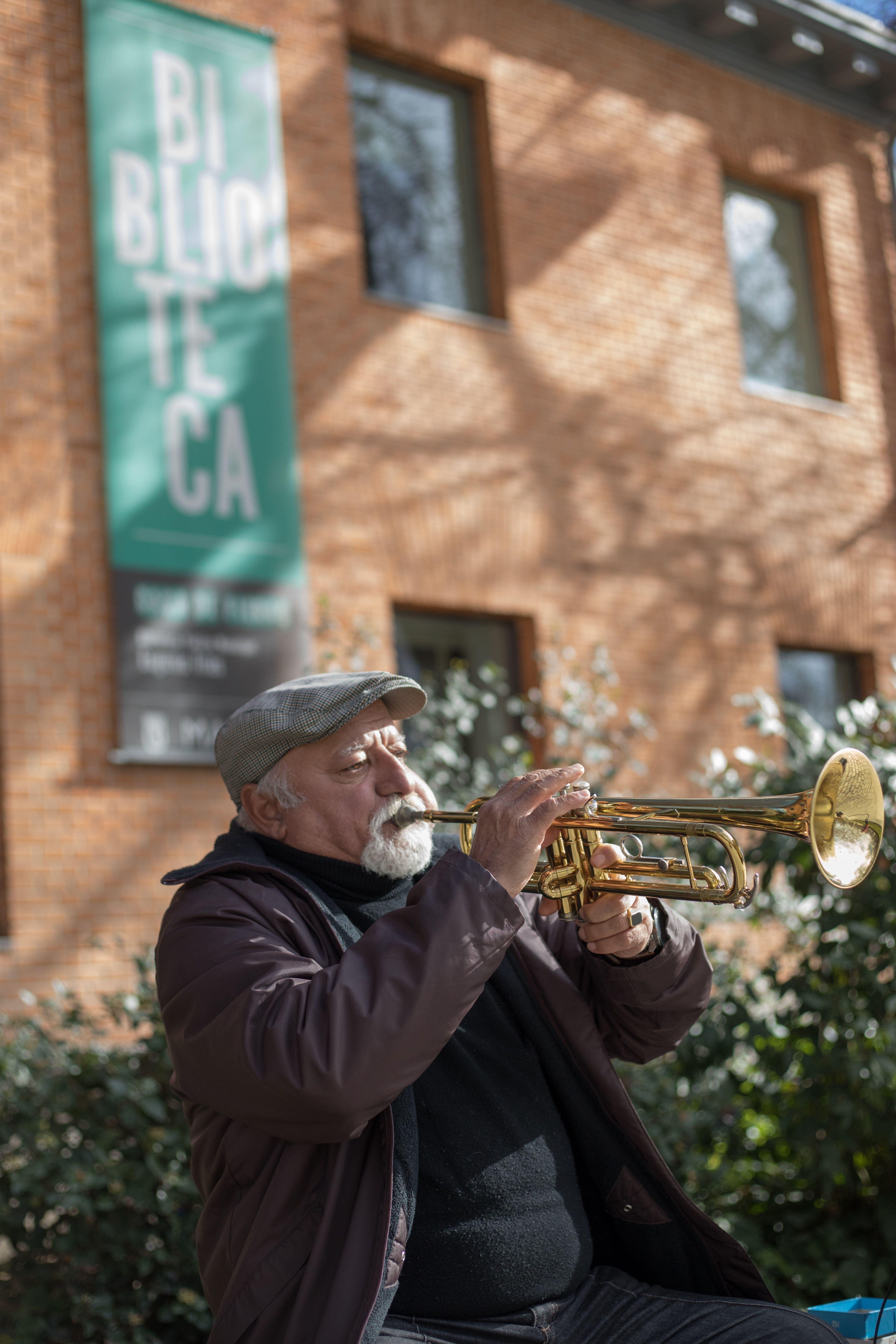 El músico toca su trompeta frente al salón de actos de la Biblioteca Eugenio Trías en el Parque del Retiro.