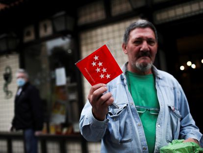 Un hombre muestra una mascarilla FPP2 que está entregando gratuitamente la Comunidad de Madrid tras recogerla en una farmacia este miércoles durante la pandemia.