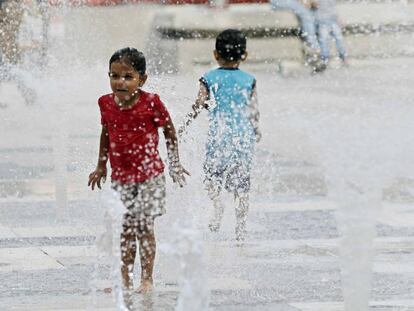 Una niña y un niño juegan con una fuente de agua en San José (Costa Rica).