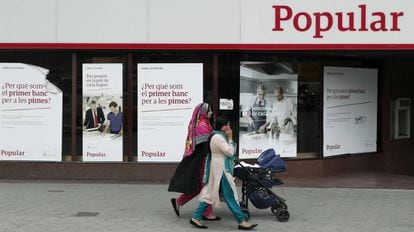 Unas mujeres pasan por delante de una oficina del Banco Popular, en Barcelona.