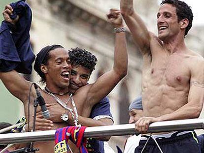 Ronaldinho, abrazado por Rijkaard, y Belletti bailan en el desfile del equipo por las calles de Barcelona.