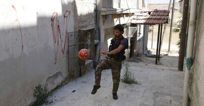 Un rebelde juega al f&uacute;tbol en el frente de Alepo (Siria), en julio de 2014.